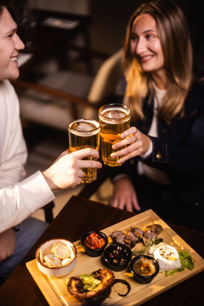 A couple enjoying beers and snacks